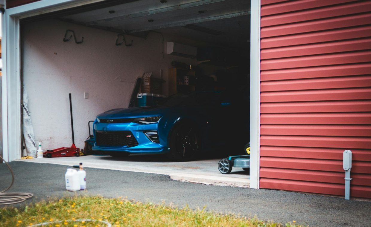 blue car parked beside red garage door