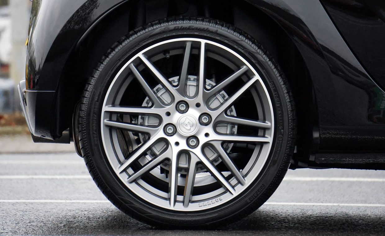 Detailed shot of a sleek car wheel and rim on a black vehicle, showcasing automotive design.