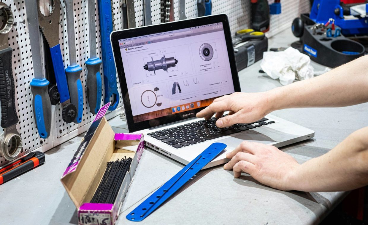a man working on a laptop computer surrounded by tools