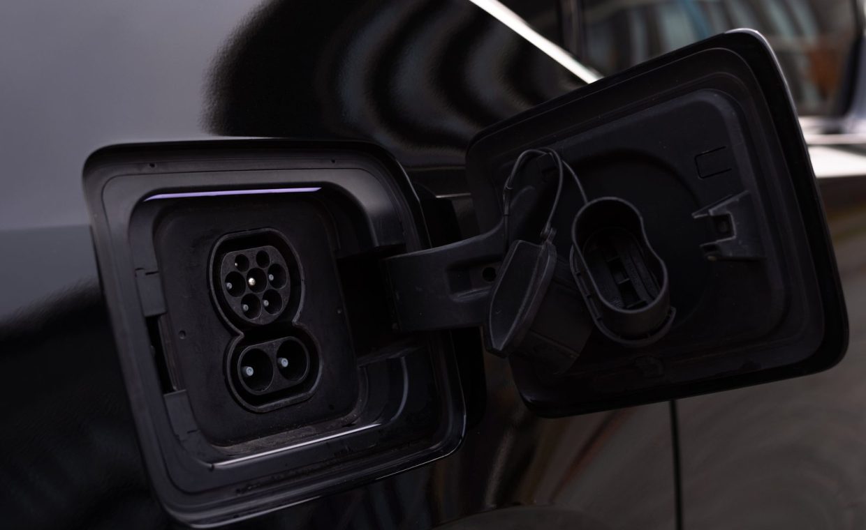Close-up image of an electric vehicle charging port on a black car.