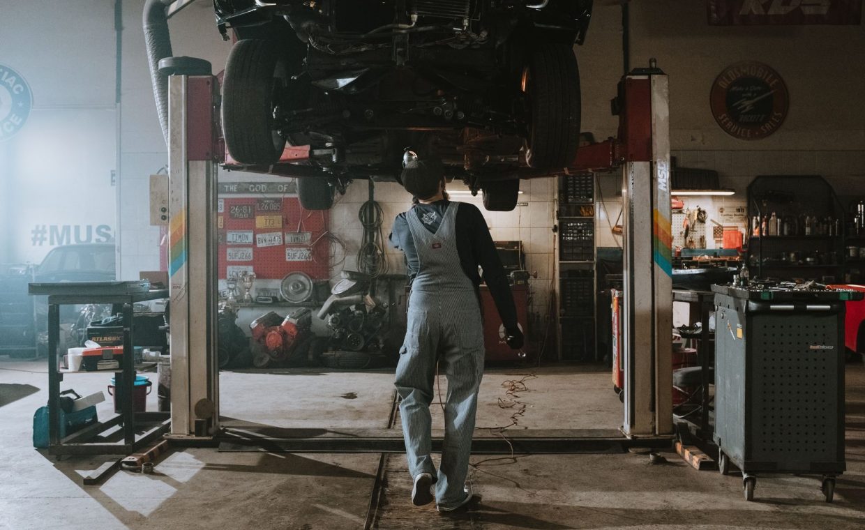 Automobile mechanic fixing a car in a repair garage, focus on service and repair work