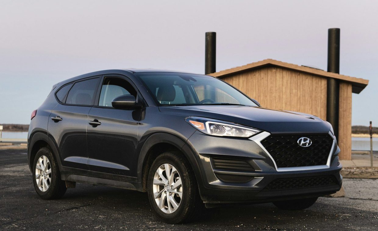 black Hyundai vehicle beside beige wooden house at daytime