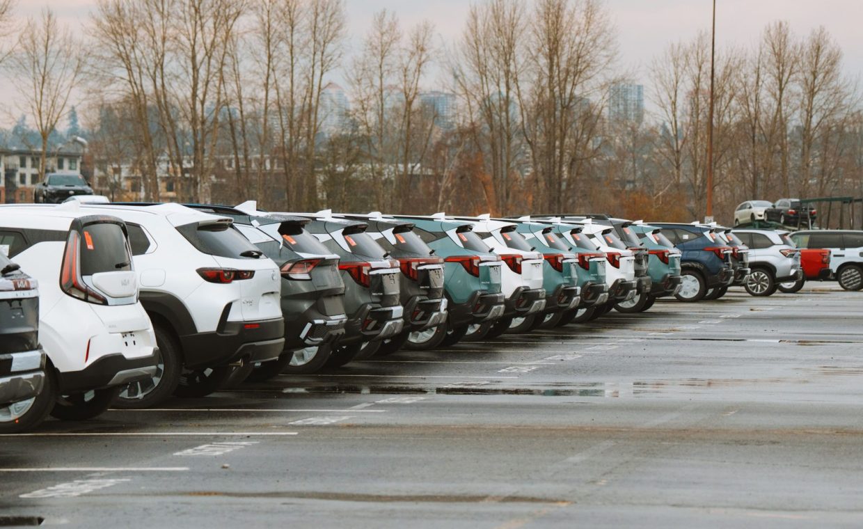 A line of parked cars in an outdoor urban parking lot on a cloudy day.