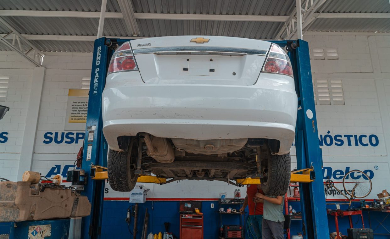 A white Chevrolet car is lifted for maintenance in an automotive repair shop.