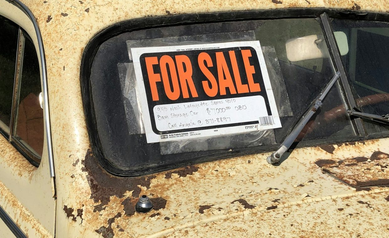a rusted out car with a for sale sign on it